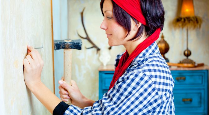 Diy fashion woman with nail and hammer on grunge house
