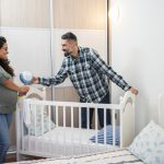 Multiethnic couple preparing bed for baby