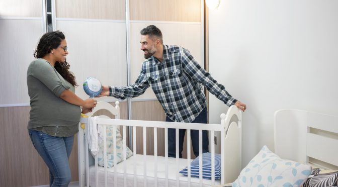 Multiethnic couple preparing bed for baby