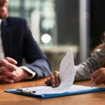 Cropped shot of a businessman and businesswoman completing paperwork together at a desk