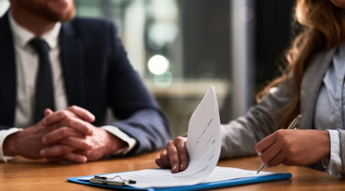 Cropped shot of a businessman and businesswoman completing paperwork together at a desk