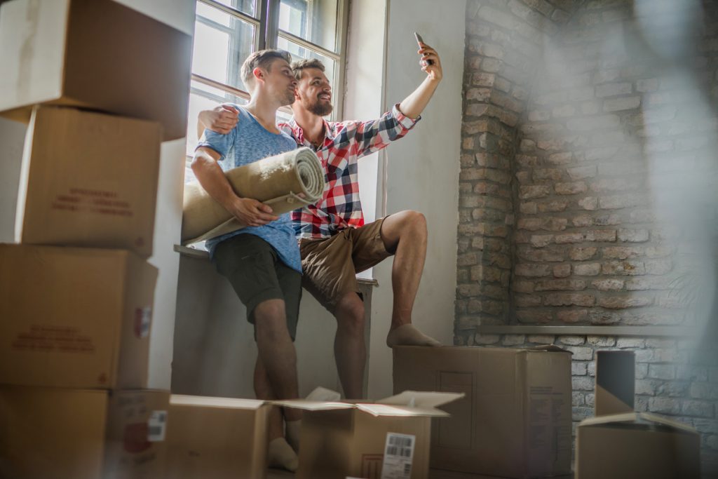 Happy embraced couple taking a selfie while relocating into new apartment.