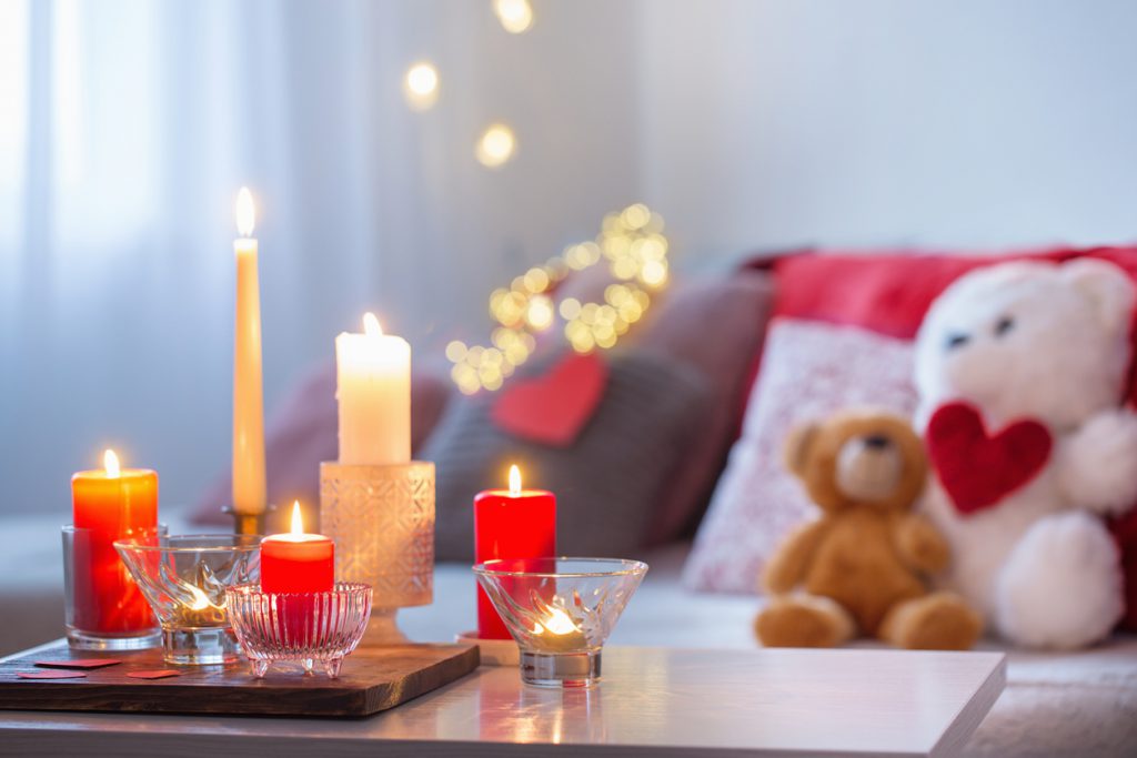 Burning candles on white table in interior. Valentines day concept