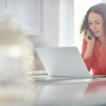 a woman in her kitchen paying a bill by phone