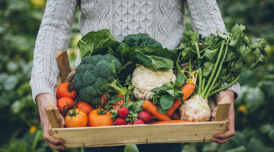 Young farmer with crate full of vegetables