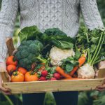 Young farmer with crate full of vegetables