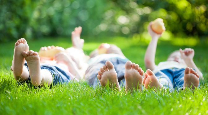 Family playing on green grass in spring park