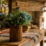 Still life with bouquet in a ceramic , wooden vase on wooden table desk. House or restaurant , resting area design with fireplace.a bouquet of green plant branches.Interior design of room with flowers.Ornamental plants cones hops in a vase. Fresh green