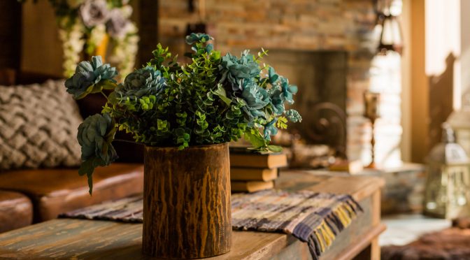 Still life with bouquet in a ceramic , wooden vase on wooden table desk. House or restaurant , resting area design with fireplace.a bouquet of green plant branches.Interior design of room with flowers.Ornamental plants cones hops in a vase. Fresh green