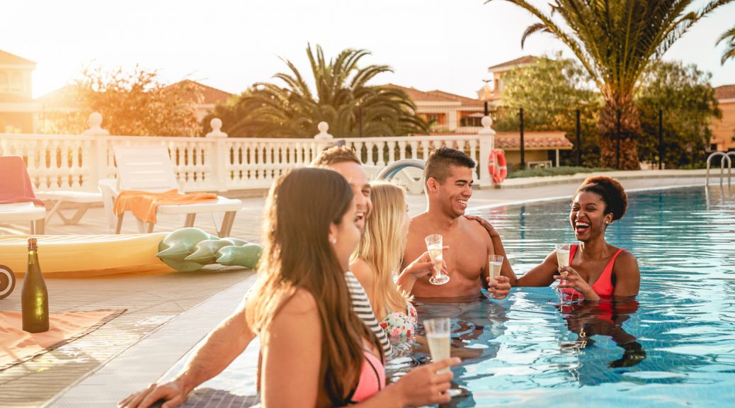 Group of happy friends making a pool party at sunset - Millennial young people laughing and having fun drinking champagne in the pool - Friendship, holidays and summer youth lifestyle concept