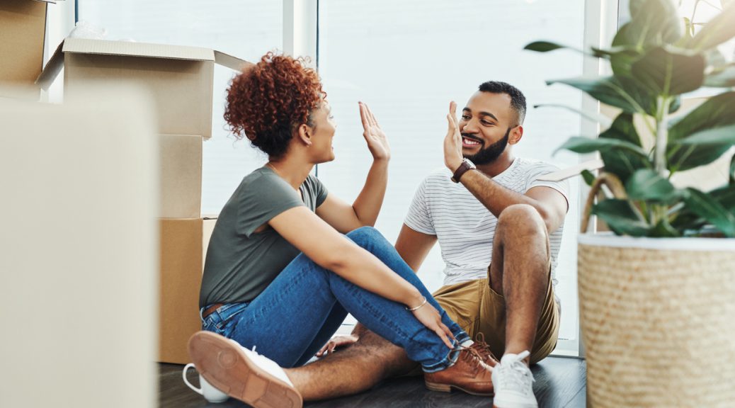Shot of a young couple giving each other a high five while moving house