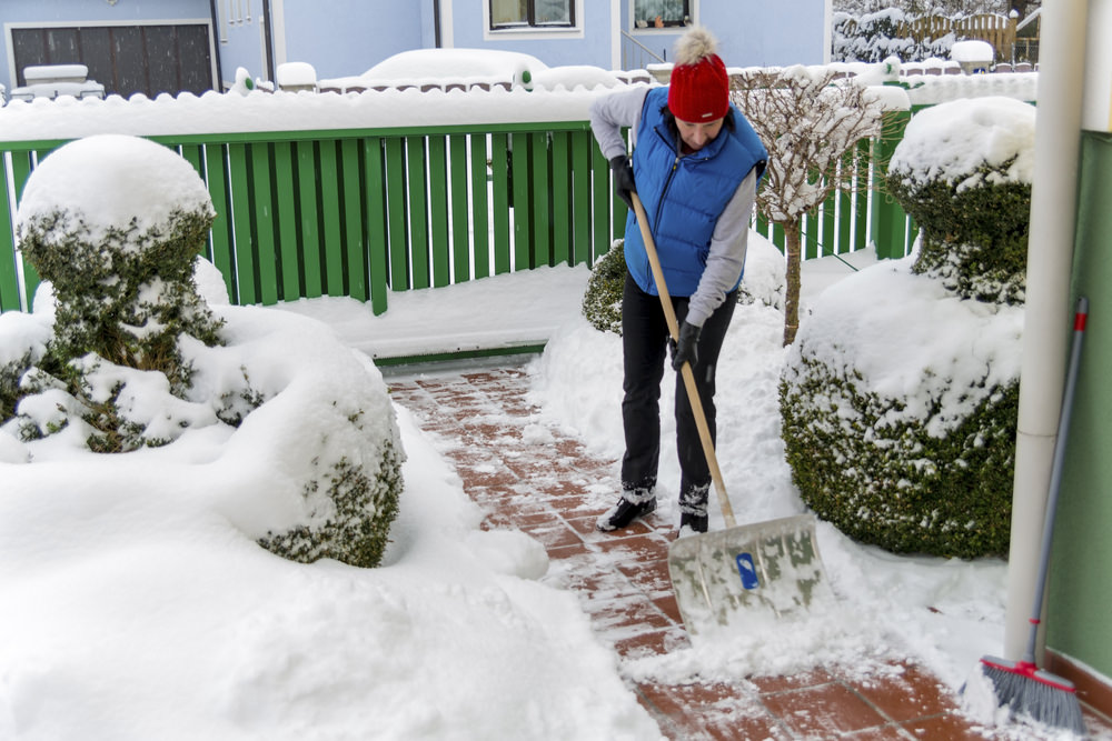 a woman is shoveling the new snow off a path. onset of winter