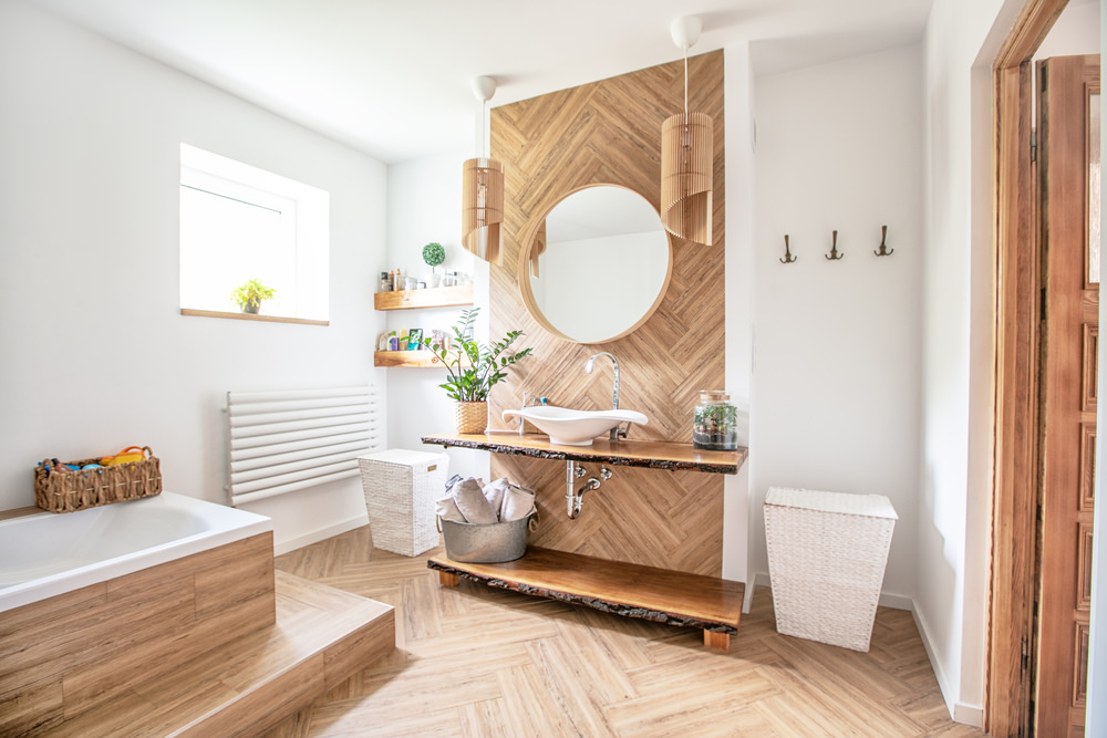 White sink on wood counter with a round mirror hanging above it. Bathroom interior.