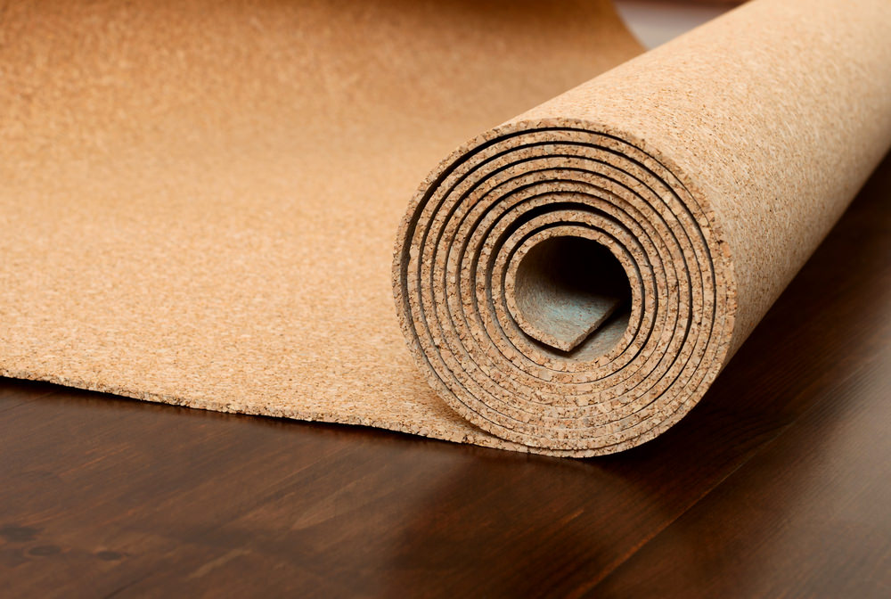 Roll of cork lies on a brown floor. The foor is made of pine and covered with semimatt lacquer